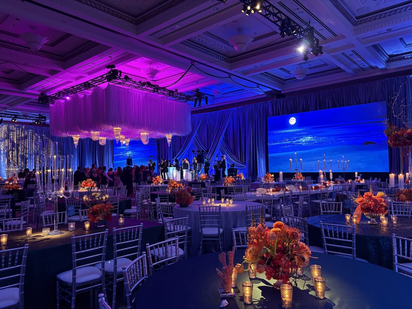 A large LED video wall showing a moonlit ocean behind the stage at a gala